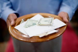 An alms basin or collection plate filled with money ready to be presented at the Altar.